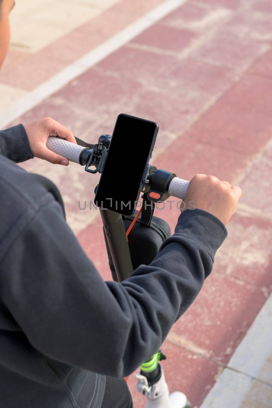 young man riding an electric skateboard outdoors, looking at route on smartphone map application, sustainable transport concept, zero CO2 emission green energy