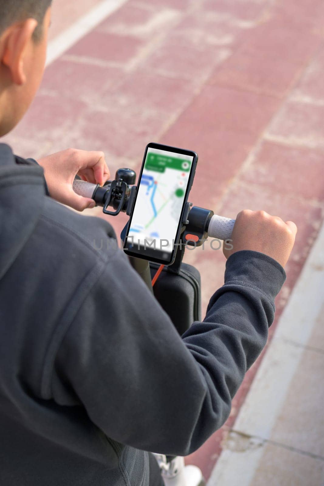young man riding an electric scooter outdoors, looking at route on smartphone map application, sustainable transport concept, zero CO2 emission green energy