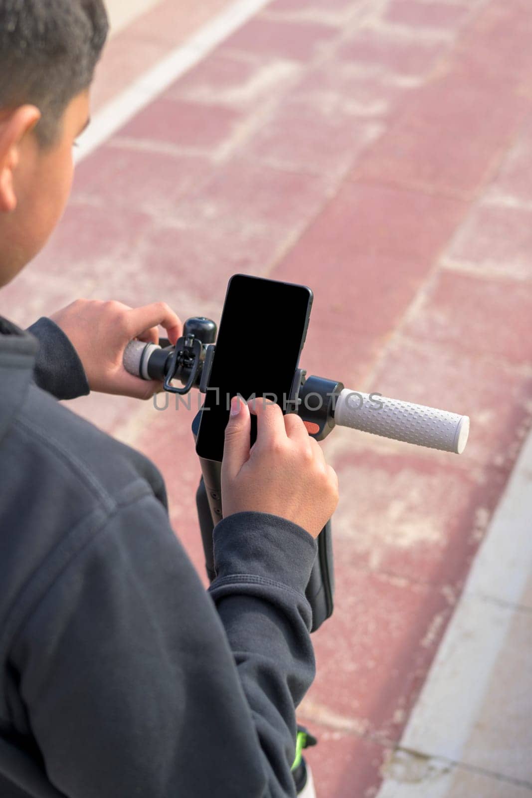 young man riding an electric skateboard outdoors, looking at route on smartphone map application, sustainable transport concept, zero CO2 emission green energy