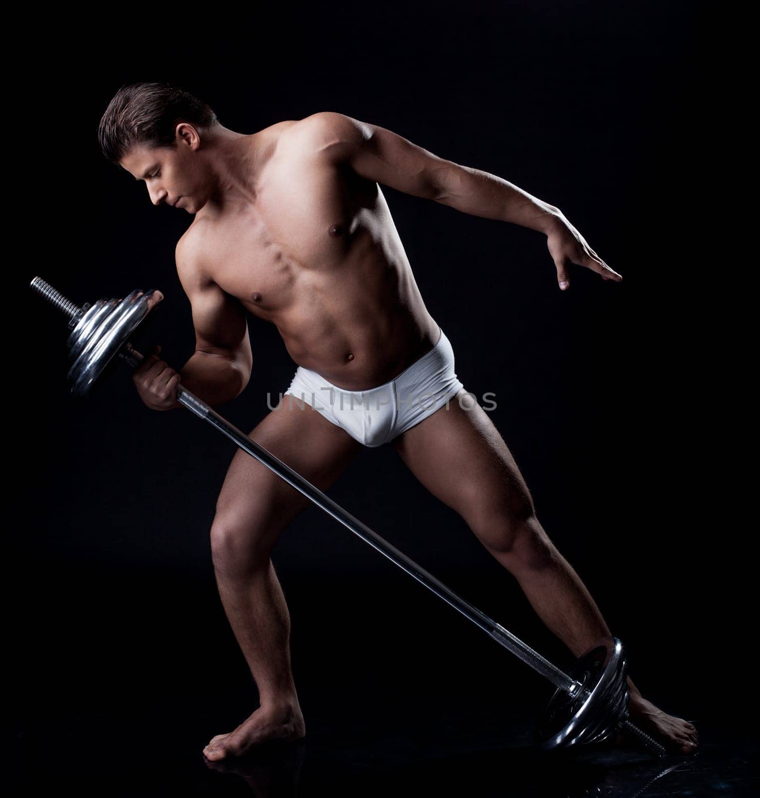 Handsome athlete lifting weights in studio, isolated on black