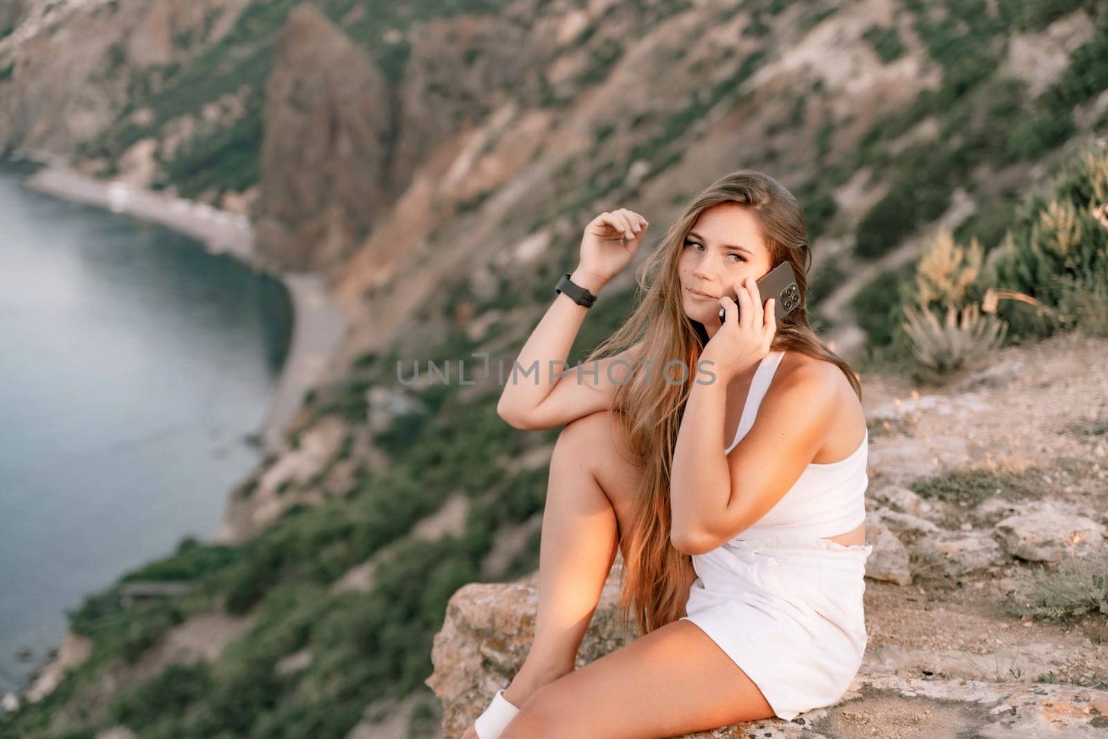 Sea phone Portrait of a happy woman on the background of the sea, dressed in white shorts and a T-shirt, long hair loose, talking on the phone by Matiunina