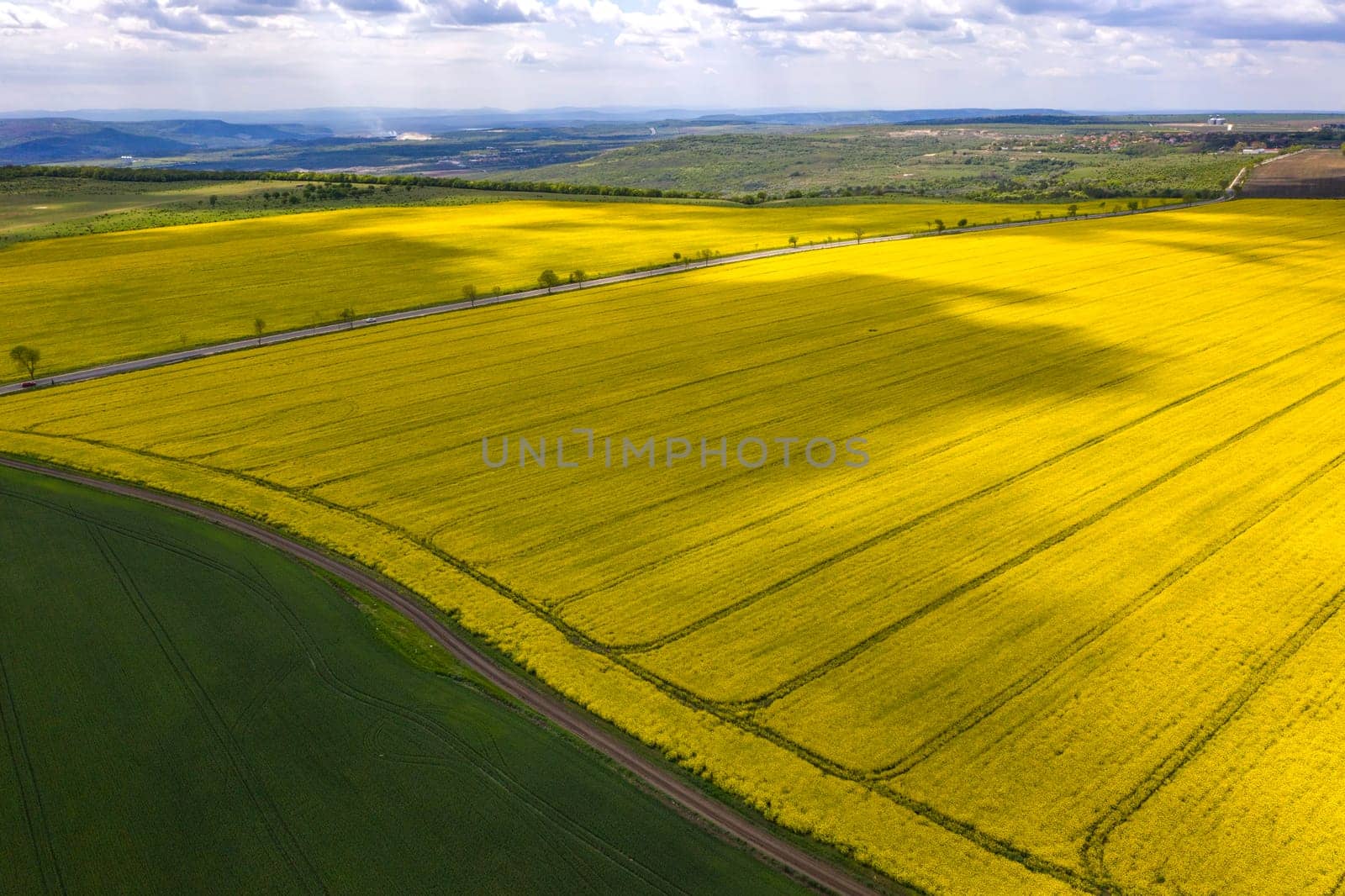 Aerial shot of fields with a tractor traces on the agricultural field sowing.