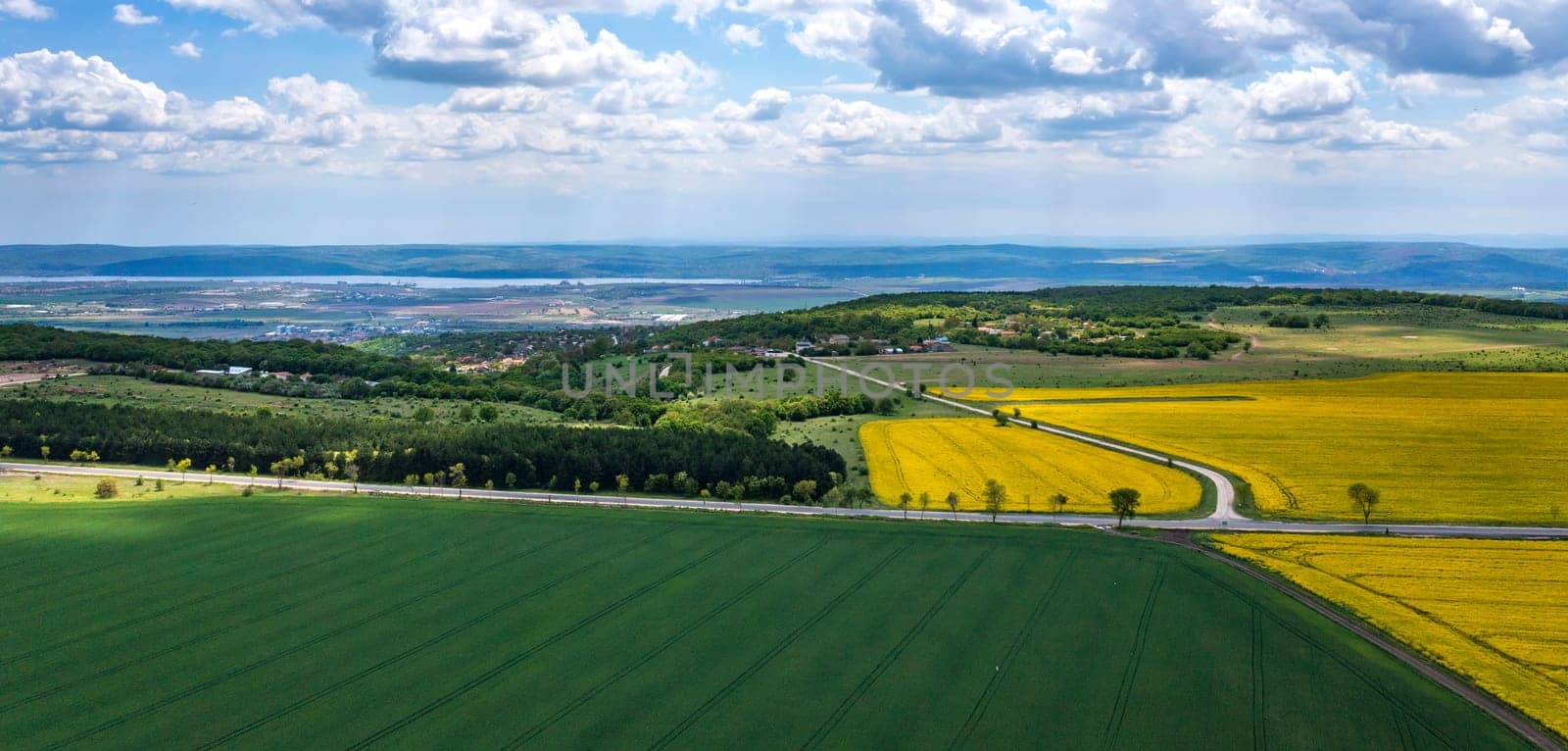 Panoramic view from drone of the vast landscape with colorful fields and road