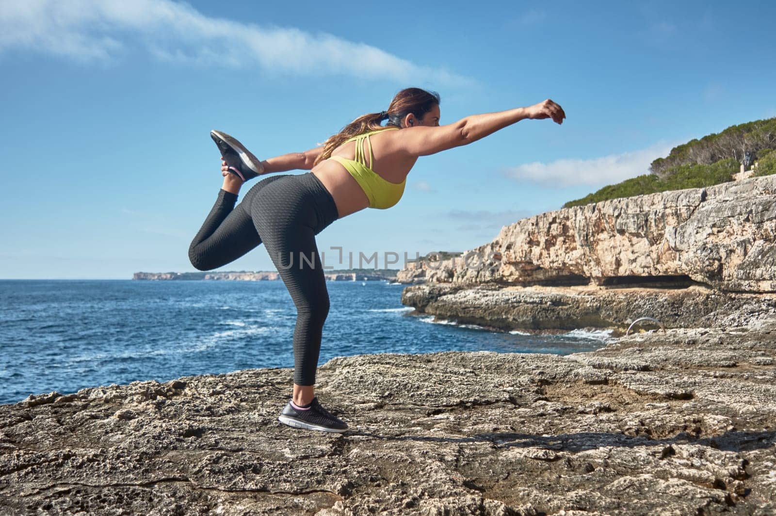 Latin woman, middle-aged, wearing sportswear, training, doing physical exercises, plank, sit-ups, climber's step, burning calories, keeping fit, outdoors by the sea, wearing headphones, smart watch