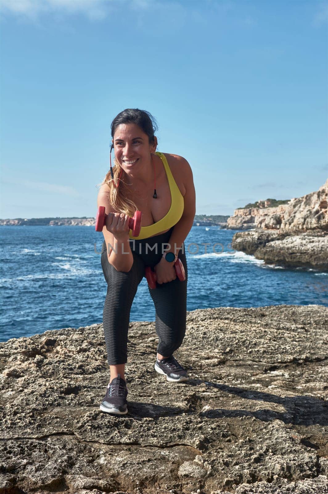 Latin woman, middle-aged, wearing sportswear, training, doing physical exercises, plank, sit-ups, climber's step, burning calories, keeping fit, outdoors by the sea, wearing headphones, smart watch,