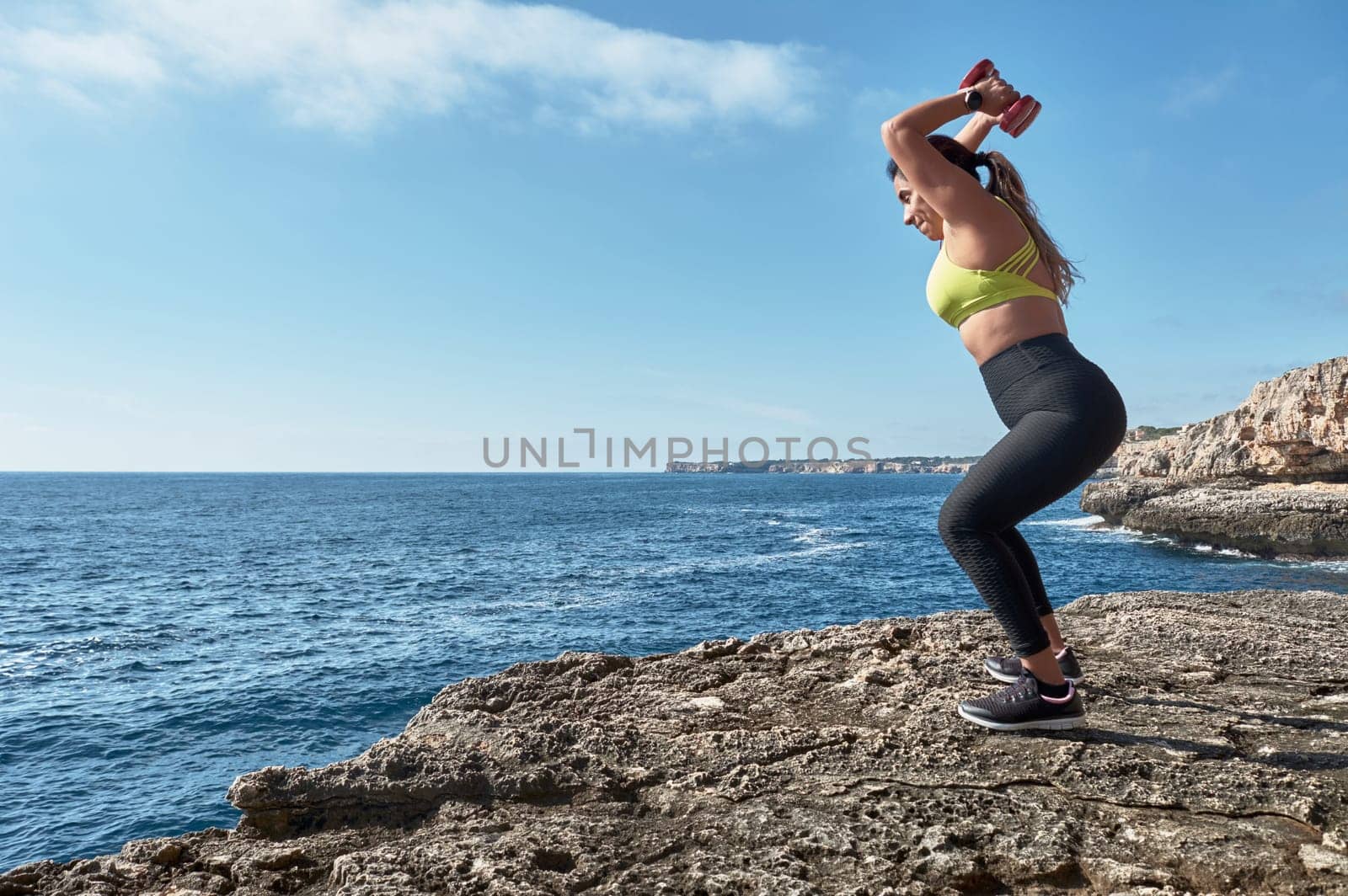 Latin woman, middle-aged, wearing sportswear, training, doing physical exercises, plank, sit-ups, climber's step, burning calories, keeping fit, outdoors by the sea, wearing headphones, smart watch,