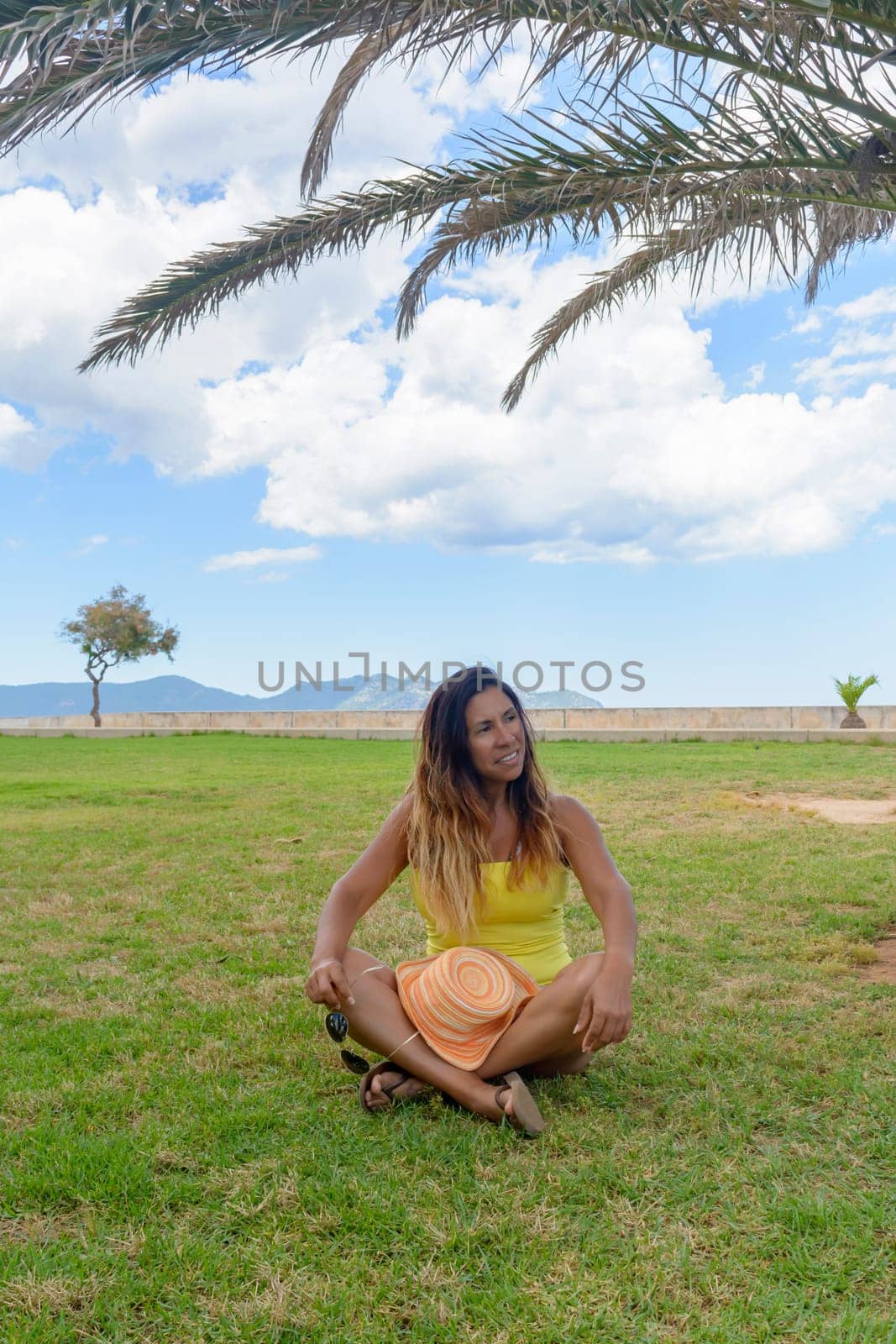 portrait of a latin woman smiling, having fun, on vacation in mallorca posing on a warm spring summer day, under a palm tree, hollidays concept,