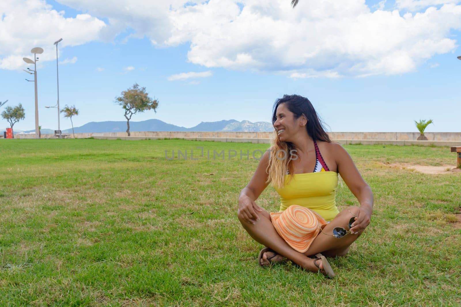 portrait of a latin woman smiling, having fun, on vacation in mallorca posing on a warm spring summer day, under a palm tree, hollidays concept,