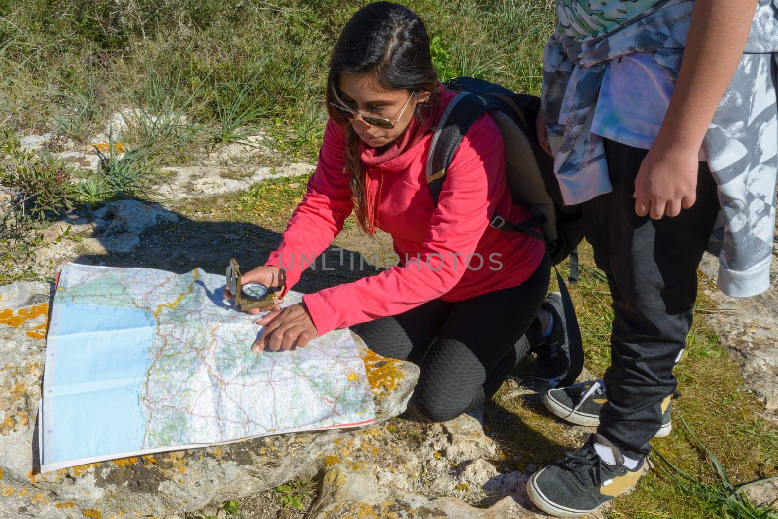 Young hiker mother and son with backpacks camping in the woods, looking at an old map with a compass. hiking in nature