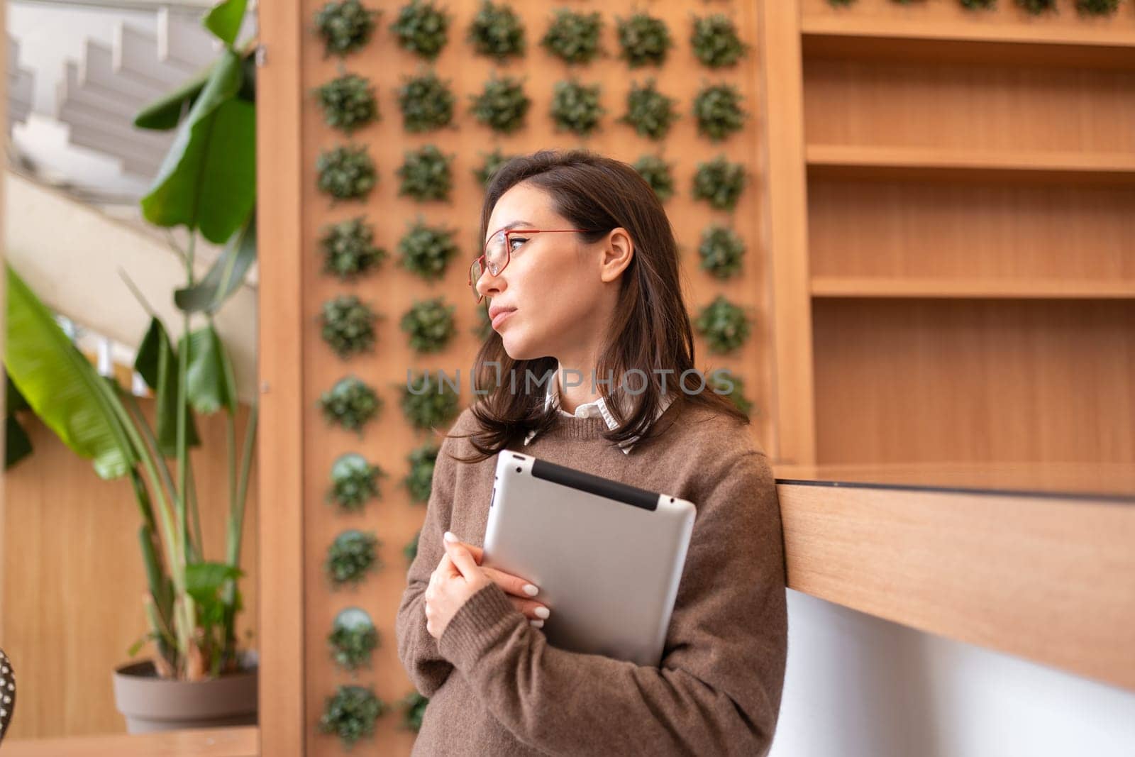 Woman in glasses with glasses standing with digital tablet looking away