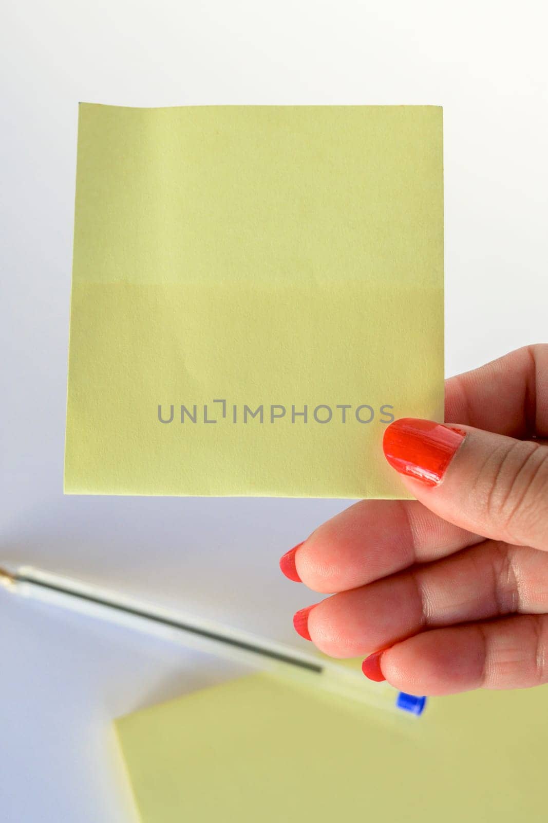 Woman's hand with painted nails holding blank letter paper on pure white background.