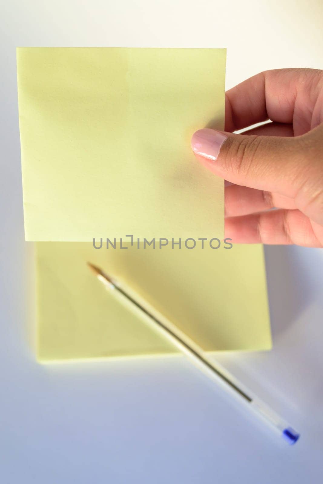 Woman's hand with painted nails holding blank letter paper on pure white background.