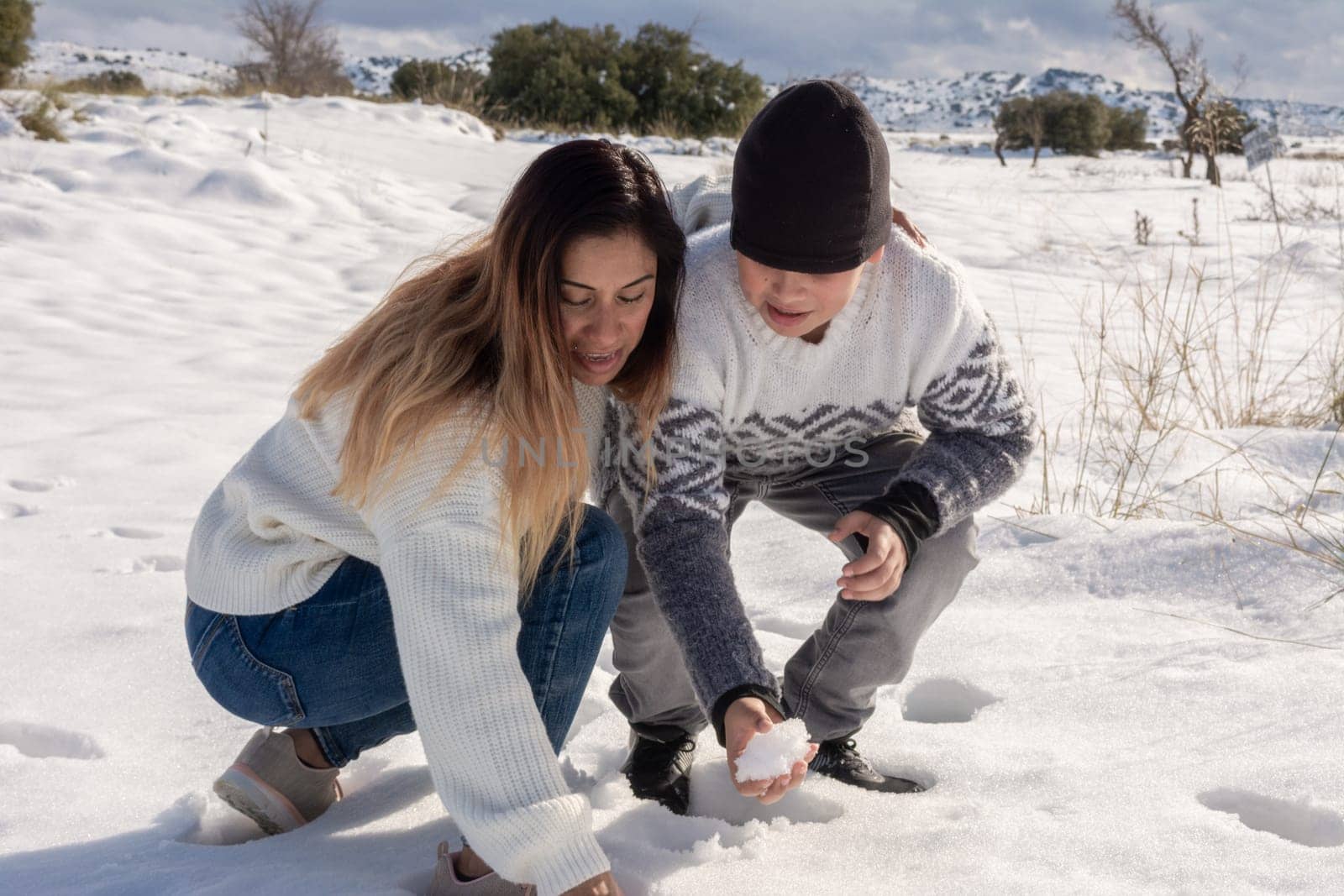 mother and son playing with snowballs in snowy field ,