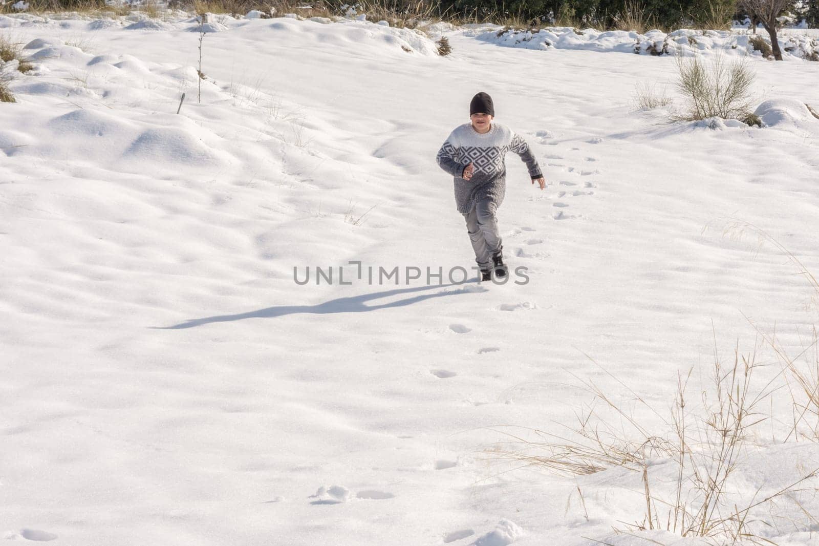 child running in the snow on a sunny day,