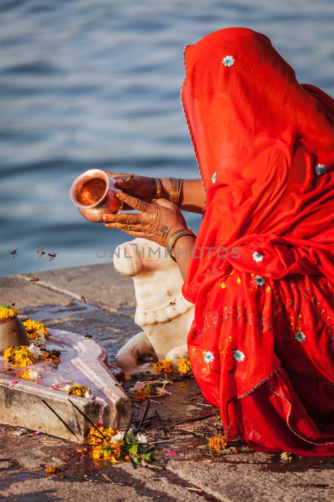 Indian woman performs morning pooja on holy river Narmada ghats by dimol