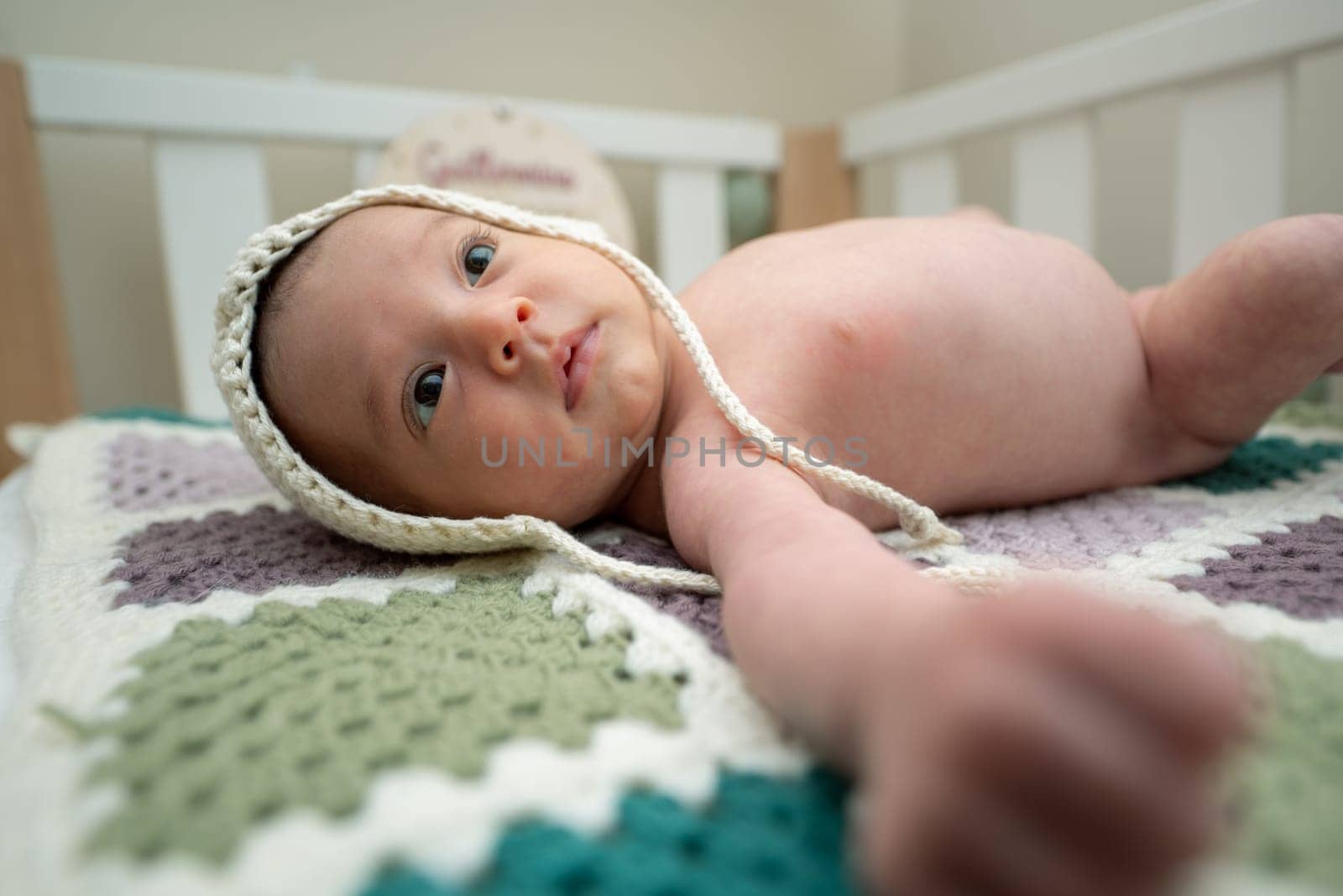 Baby with two months of life in his crib with a wool cap.