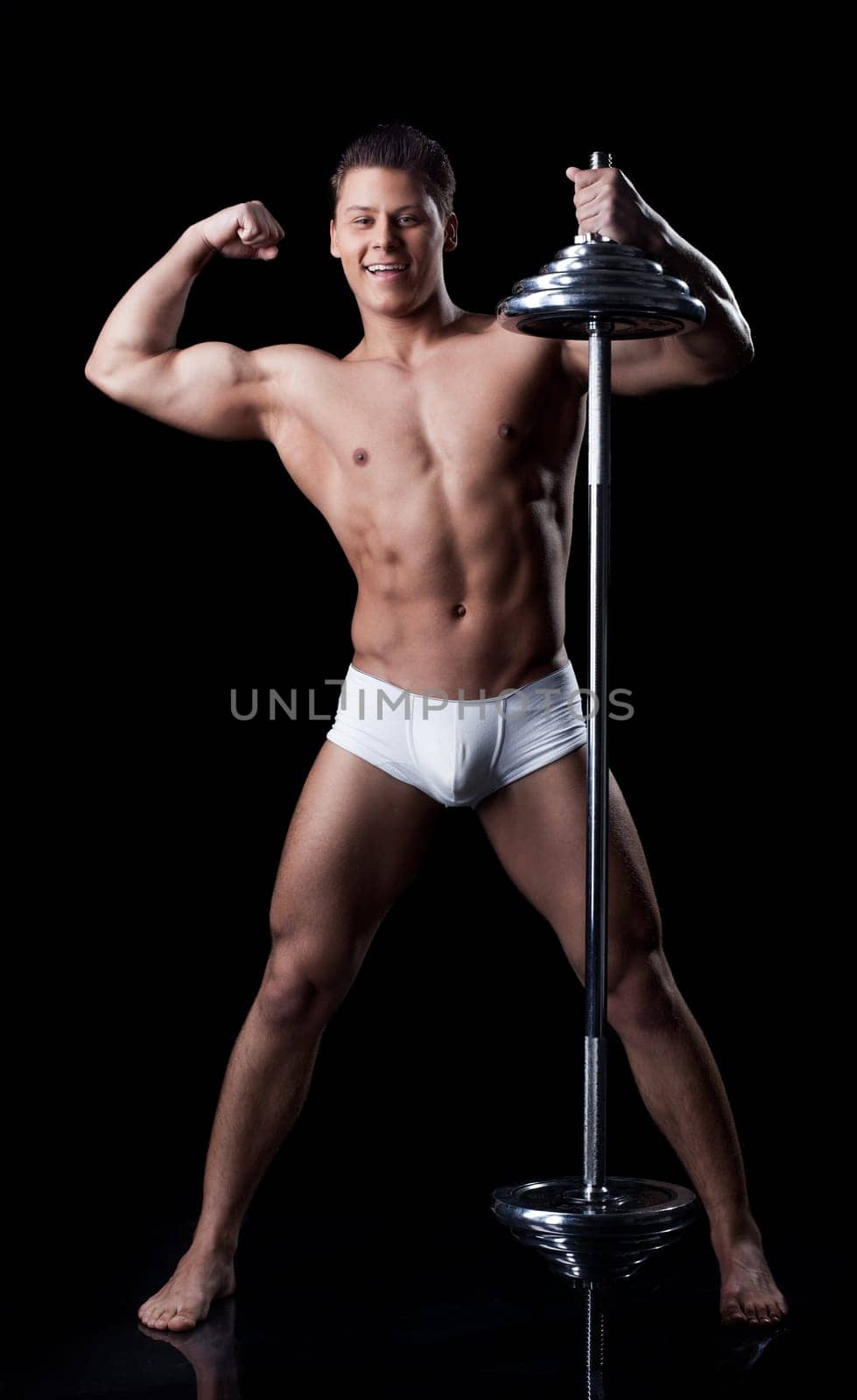 Handsome muscular sportsman posing with rod, isolated on black