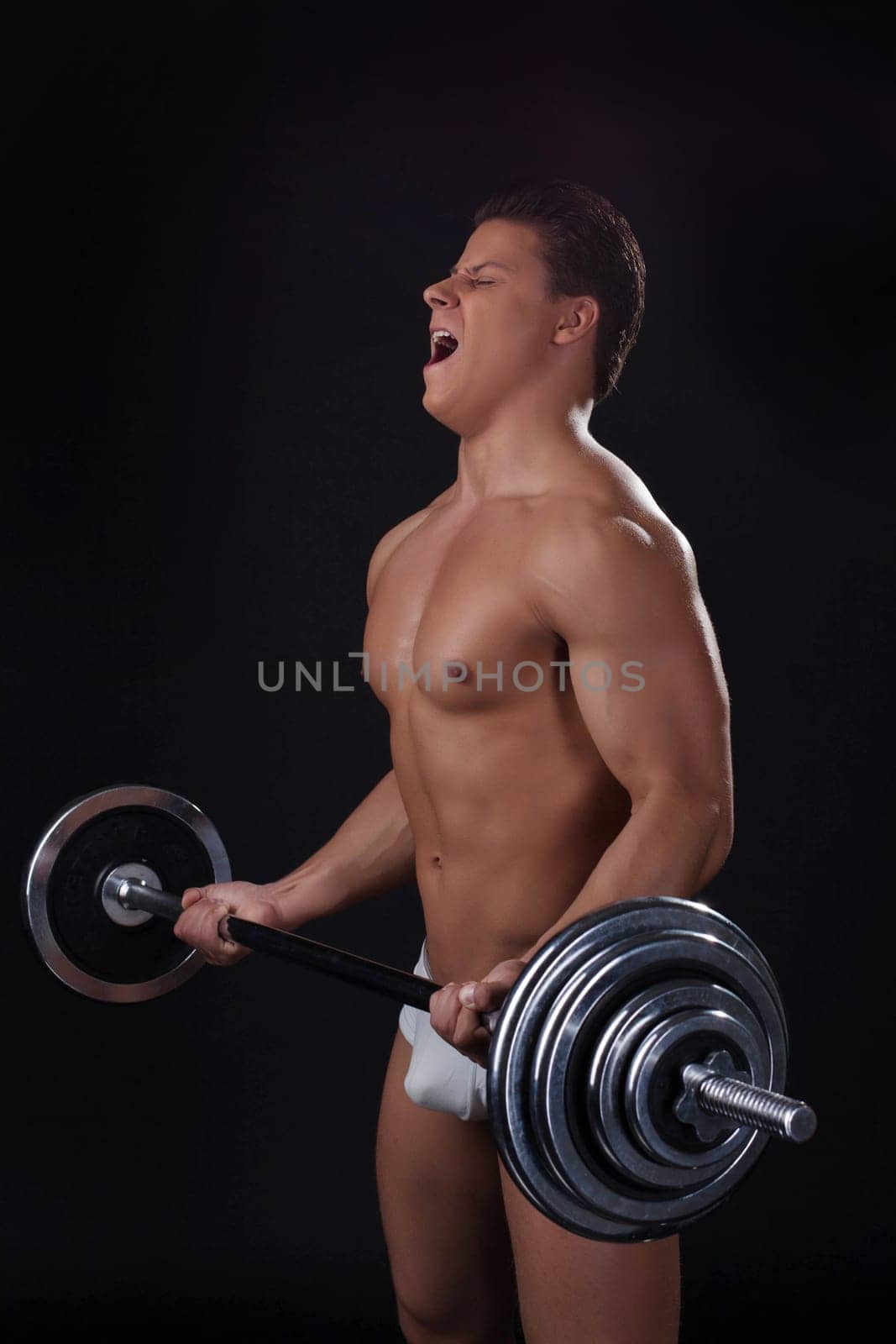 Portrait of young athlete lifting weights, isolated on black