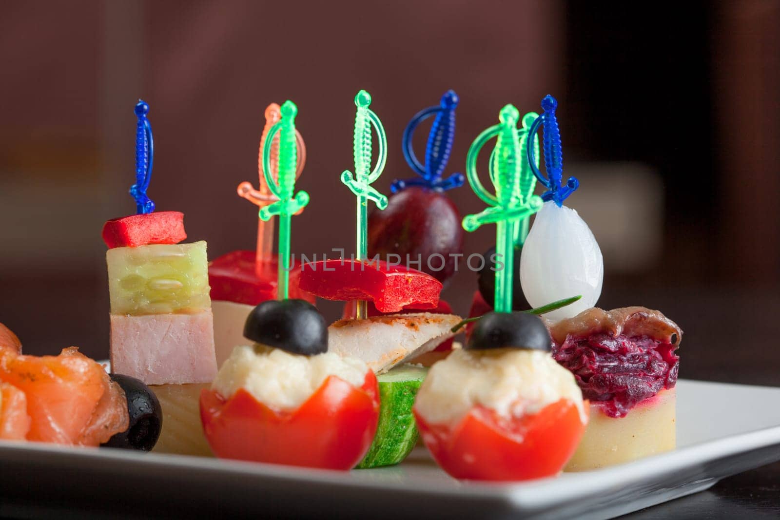 Dish with delicious small canapes on skewers, close-up