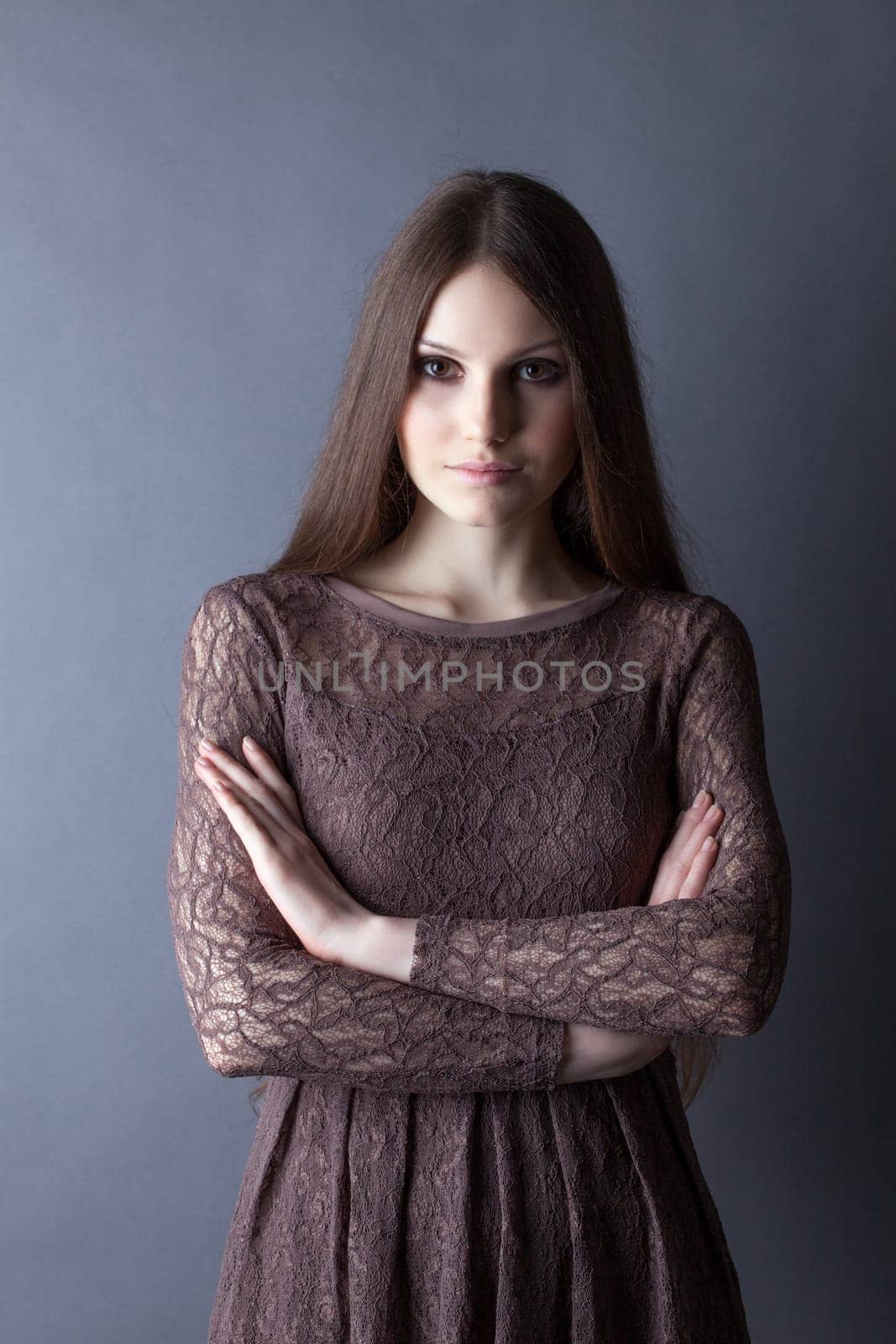 Lovely brunette posing in lace dress on gray background, close-up