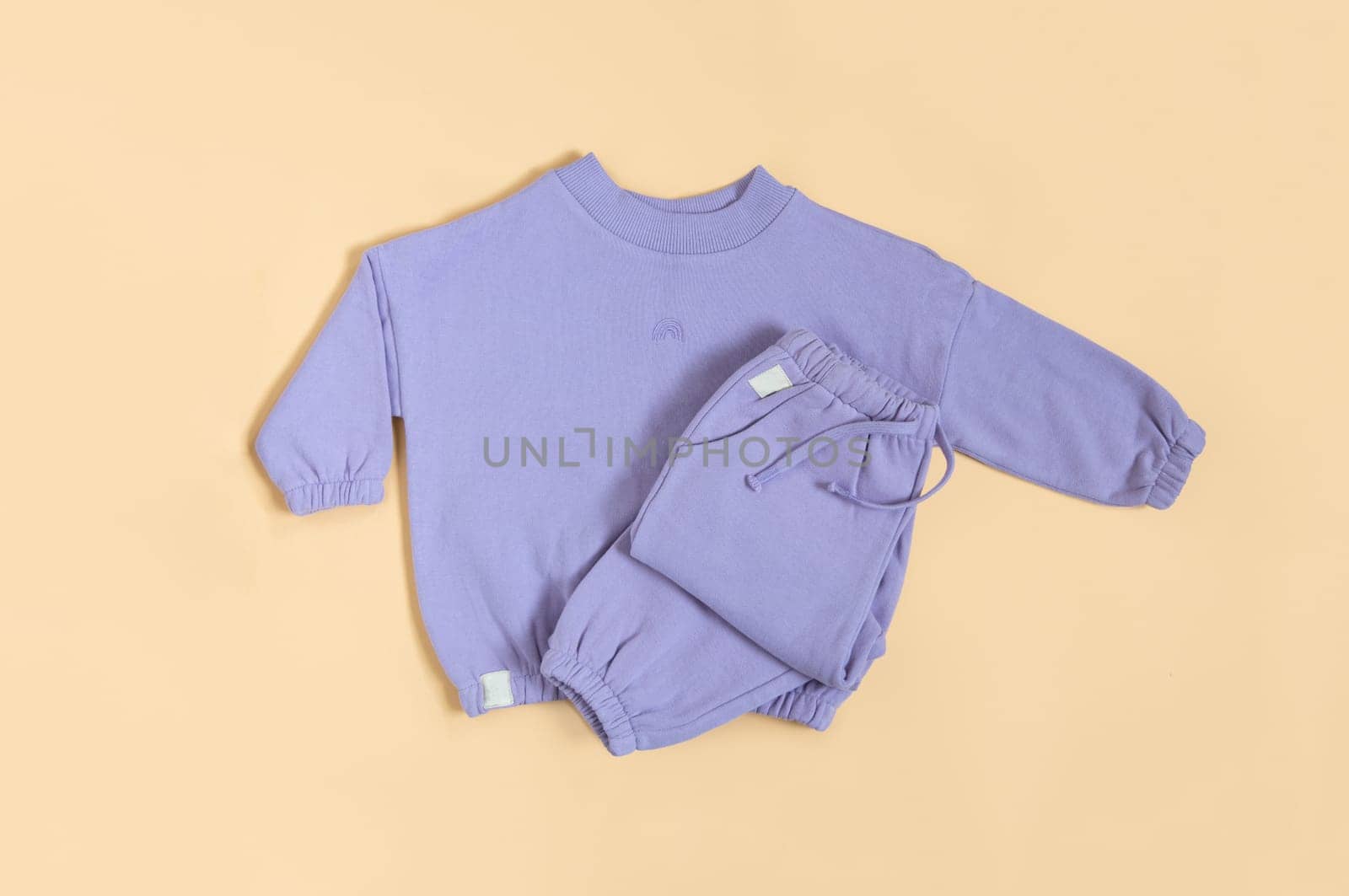 Stylish lilac children's spring, autumn sport costume. Soft touch, warm joggers and sweatshirt. Fashion kids outfit for spring, autumn and winter. Flat lay, top view