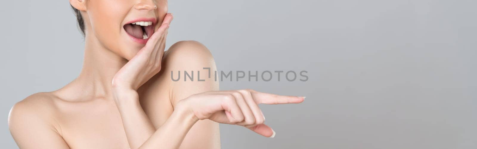 Closeup glamorous beautiful woman with perfect makeup clean skin pointing finger in copyspace isolated background. Promotion indicated by hand gesture concept for skincare product advertisement.