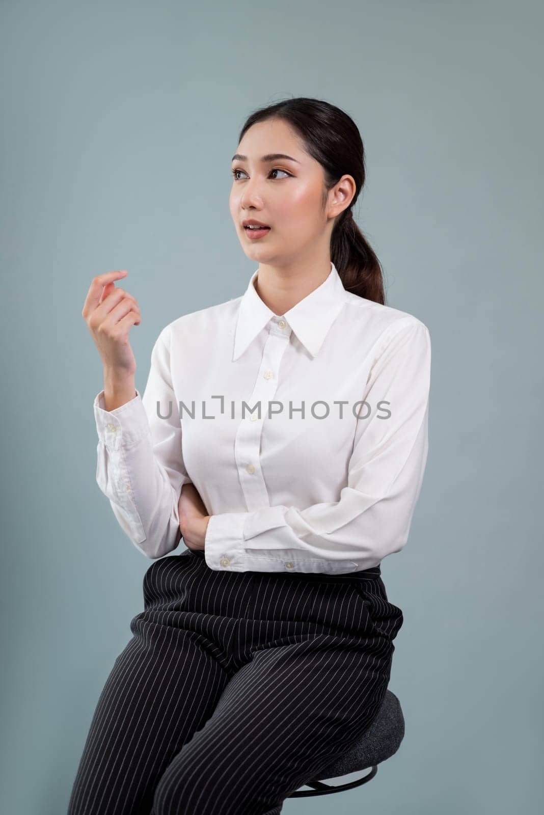 Confident young businesswoman sitting on isolated background. Enthusiastic by biancoblue