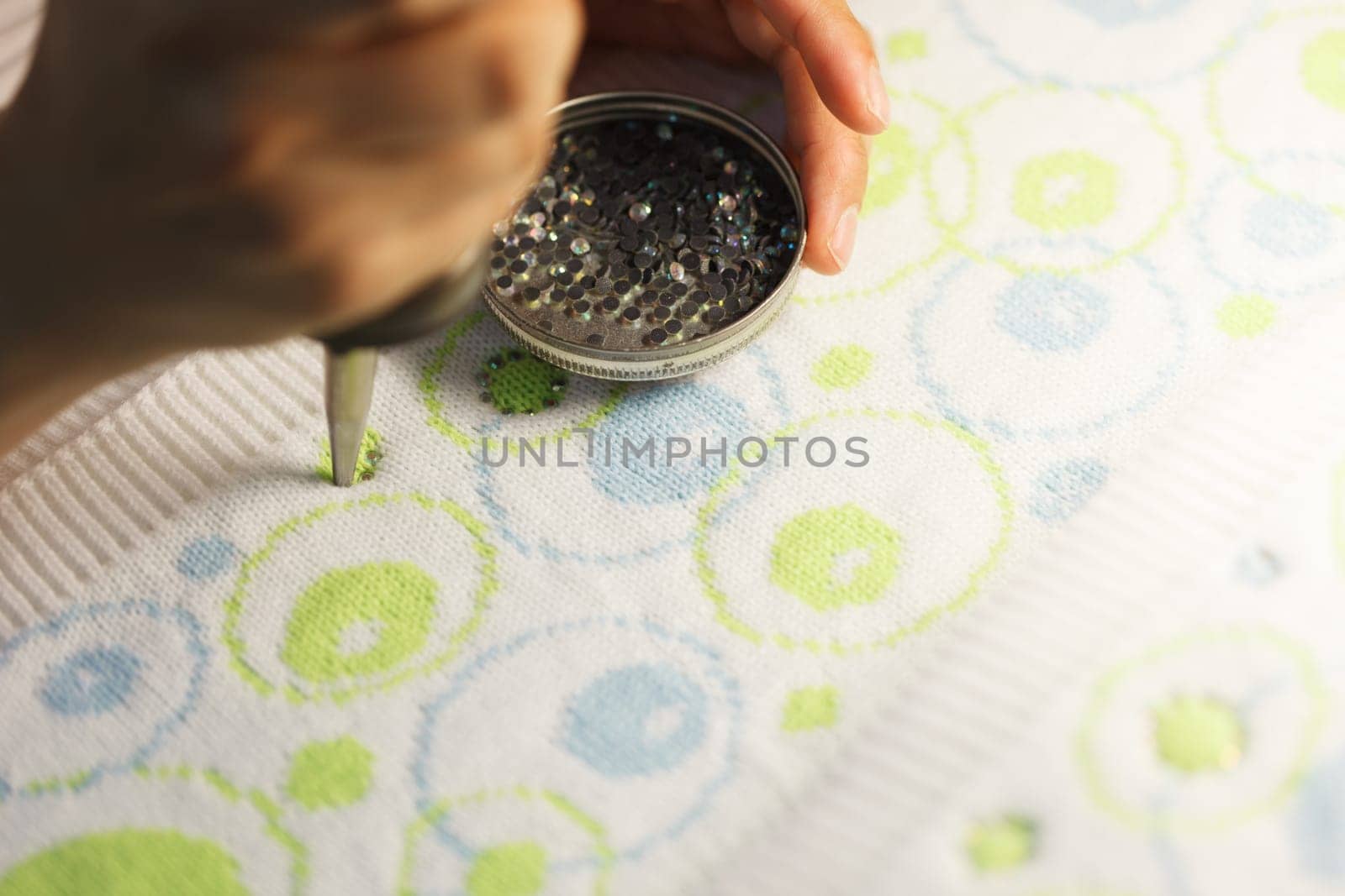 Woman glueing sequins to colorful fabrics, close-up
