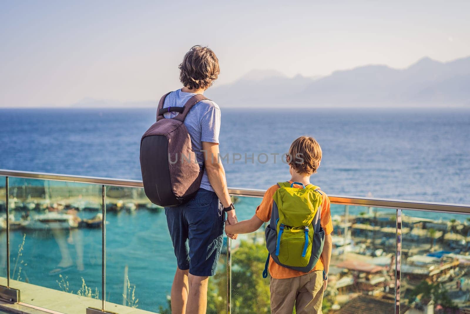 Father and son tourists in Old town Kaleici in Antalya. Turkiye. Panoramic view of Antalya Old Town port, Taurus mountains and Mediterrranean Sea, Turkey. Traveling with kids concept.