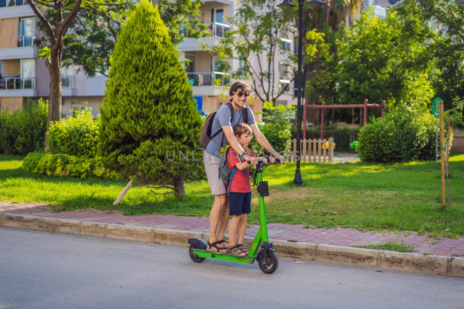 The father riding the electric scooter with his son in the city.