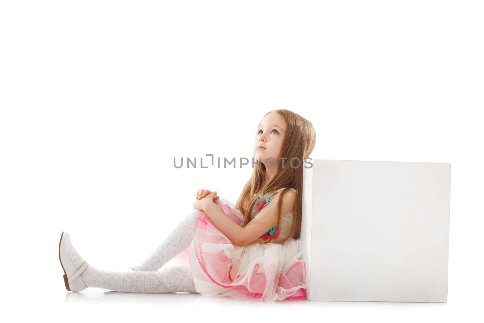 Dreamy little girl posing with cube in studio, isolated on white