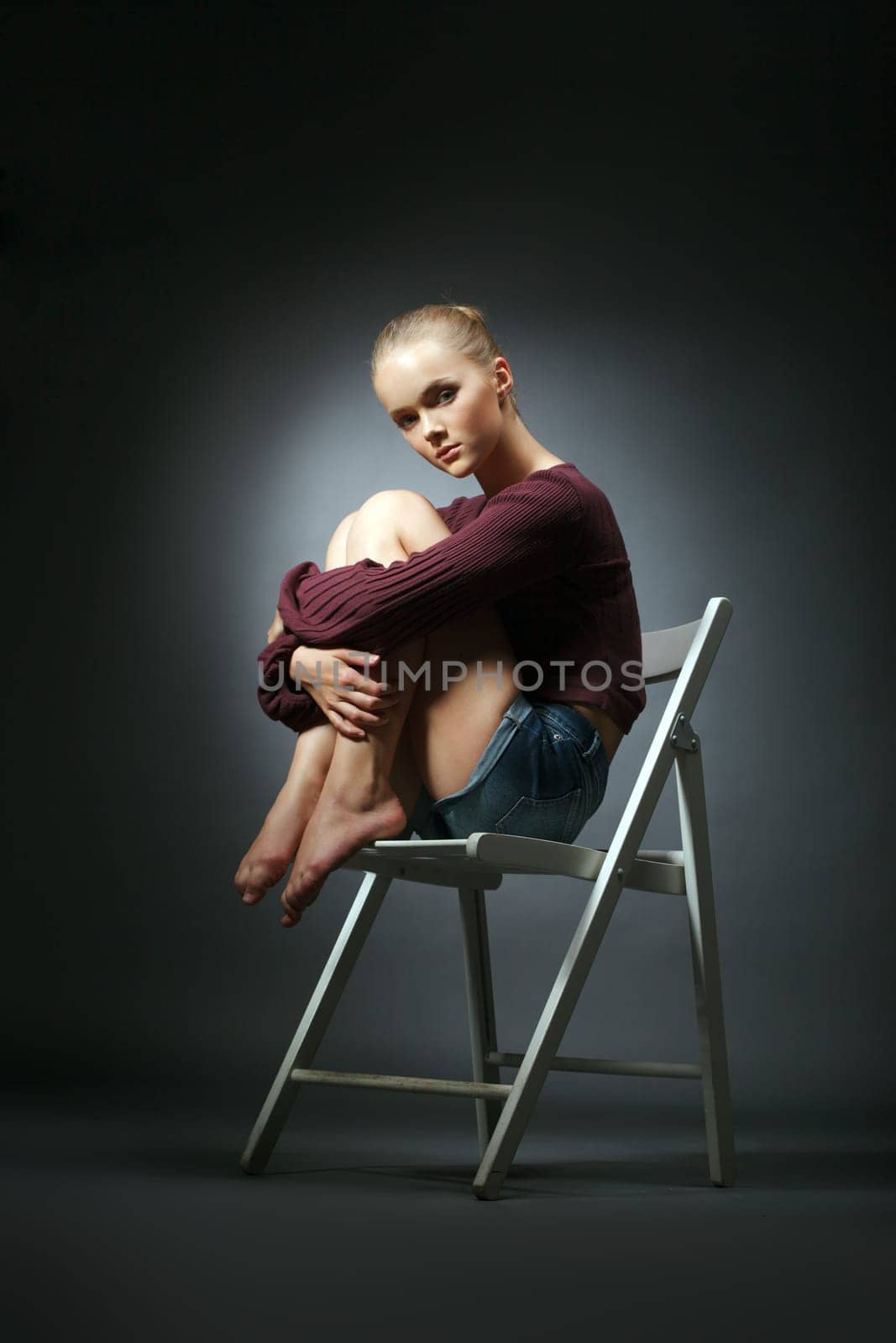 Refined model in stylish clothes sitting on chair, close-up