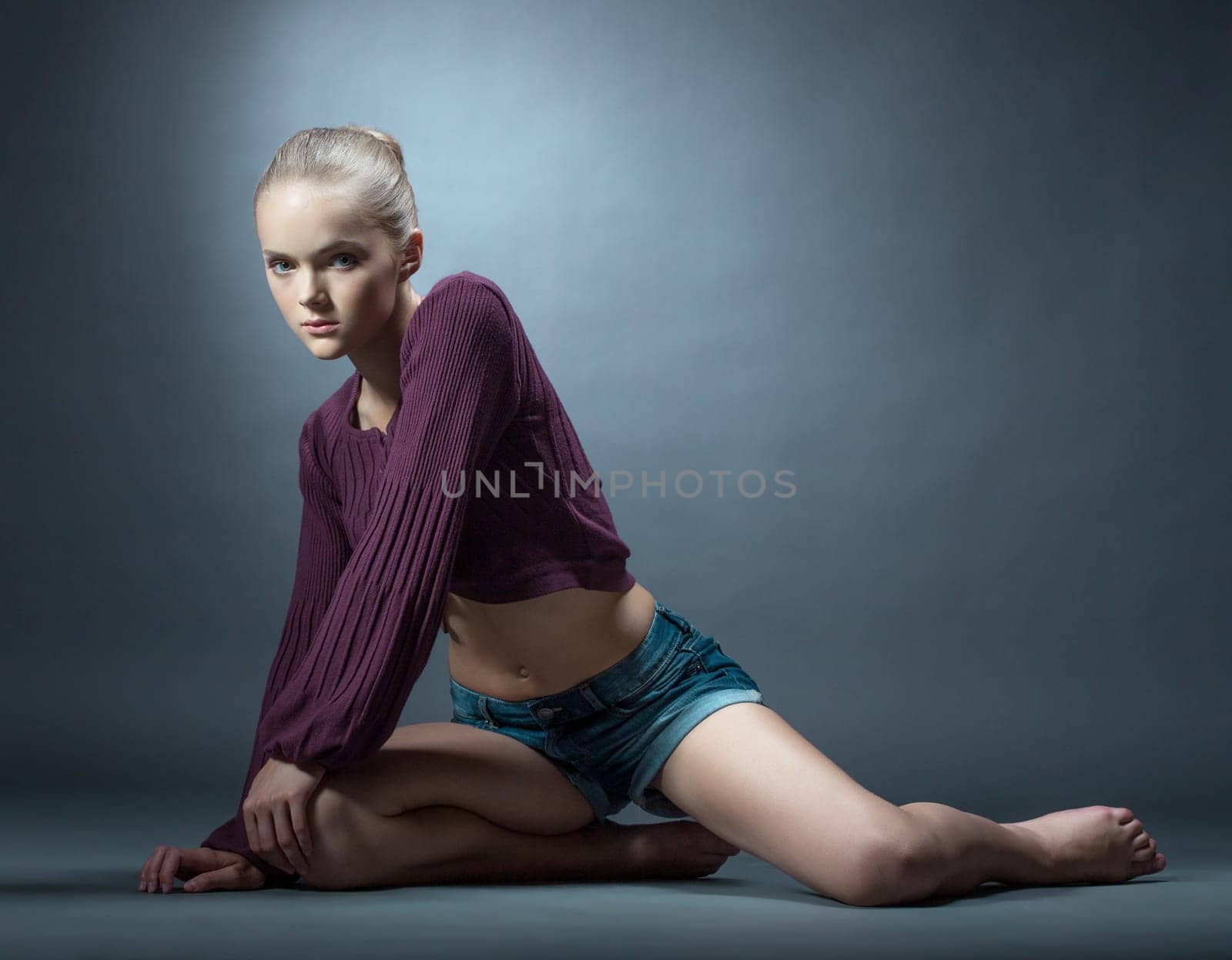 Slim young girl posing in fashionable clothes, on gray background
