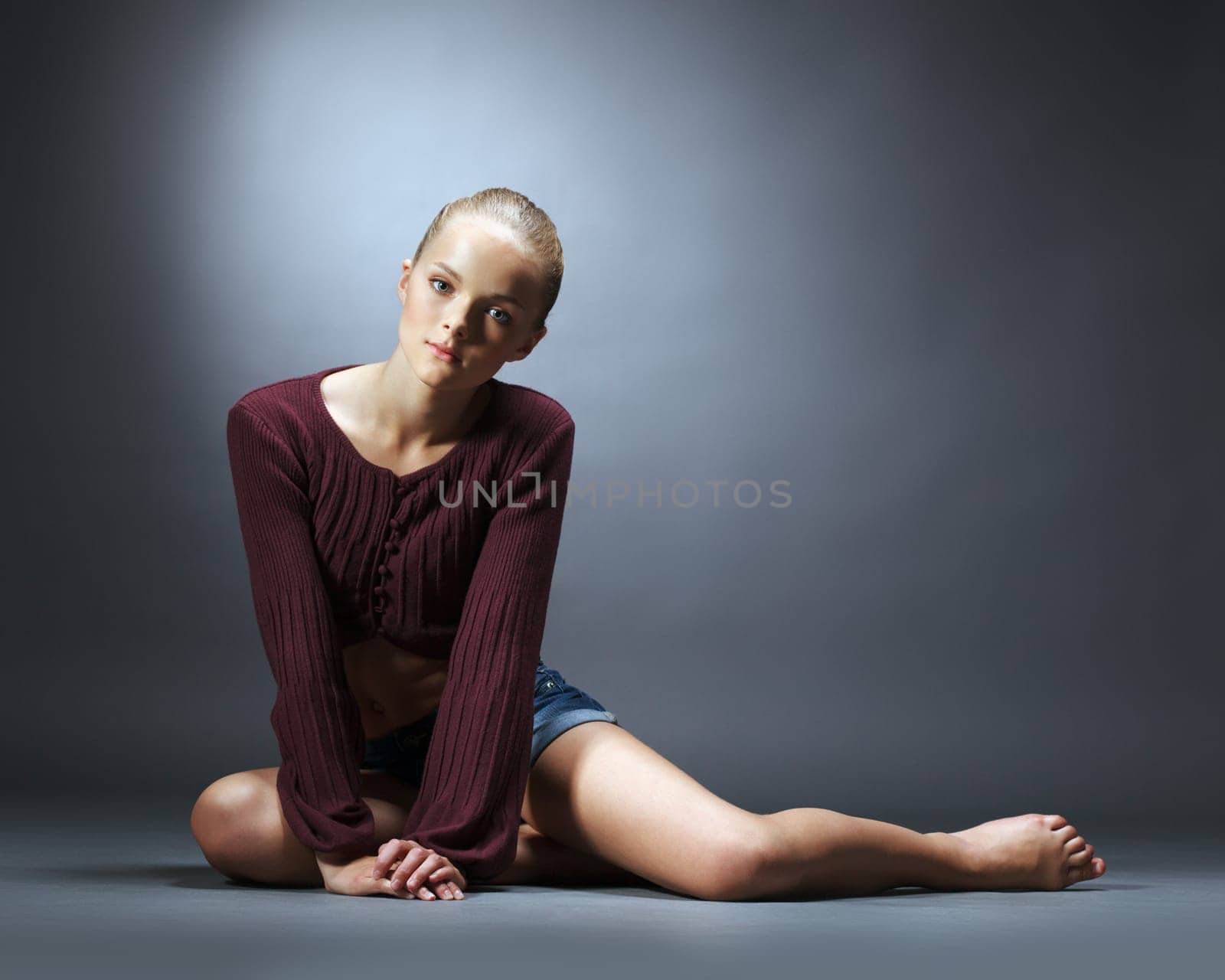 Sensual young girl advertises fashionable clothes, on gray background