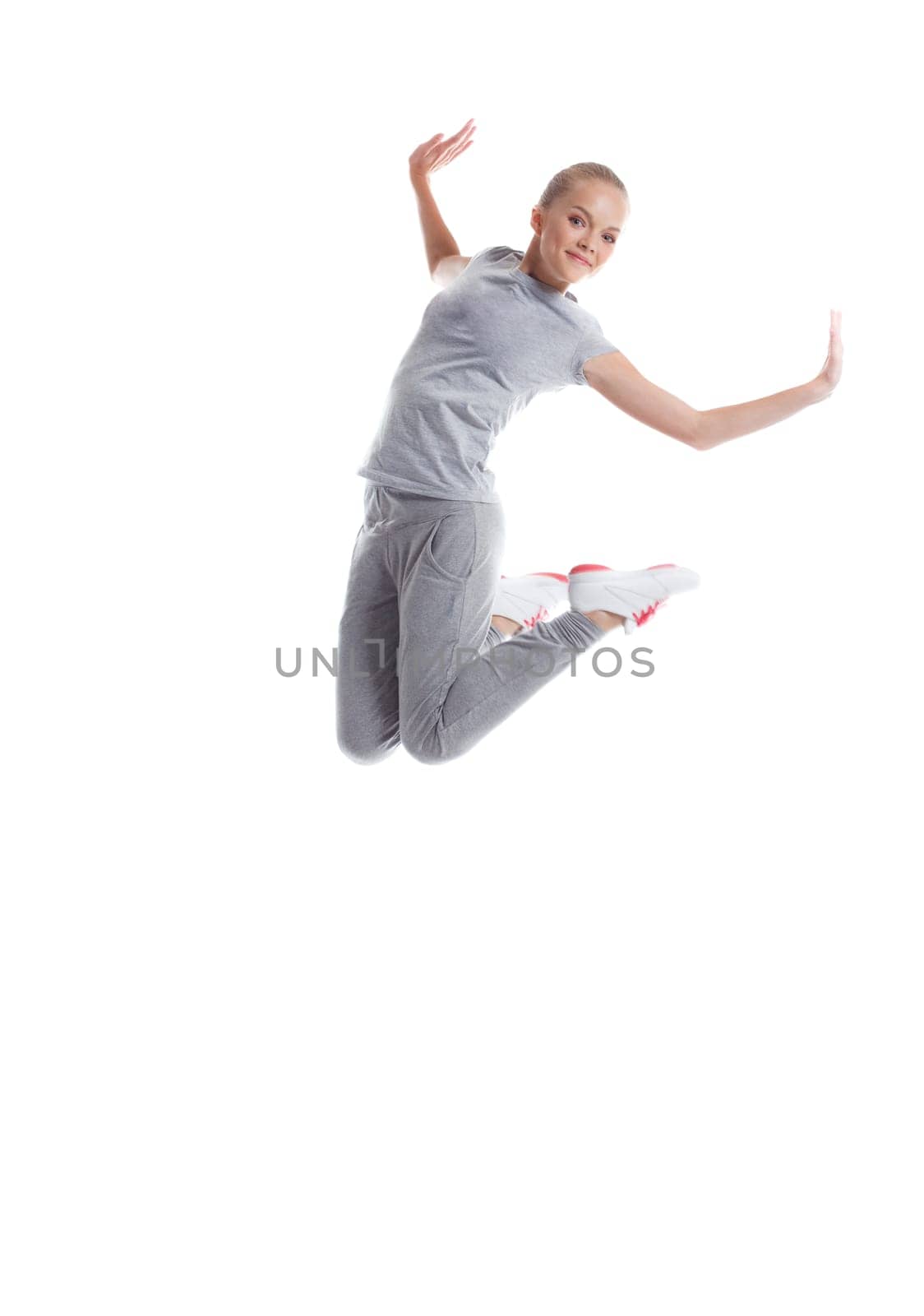 Image of smiling sporty girl jumping in studio, isolated on white background