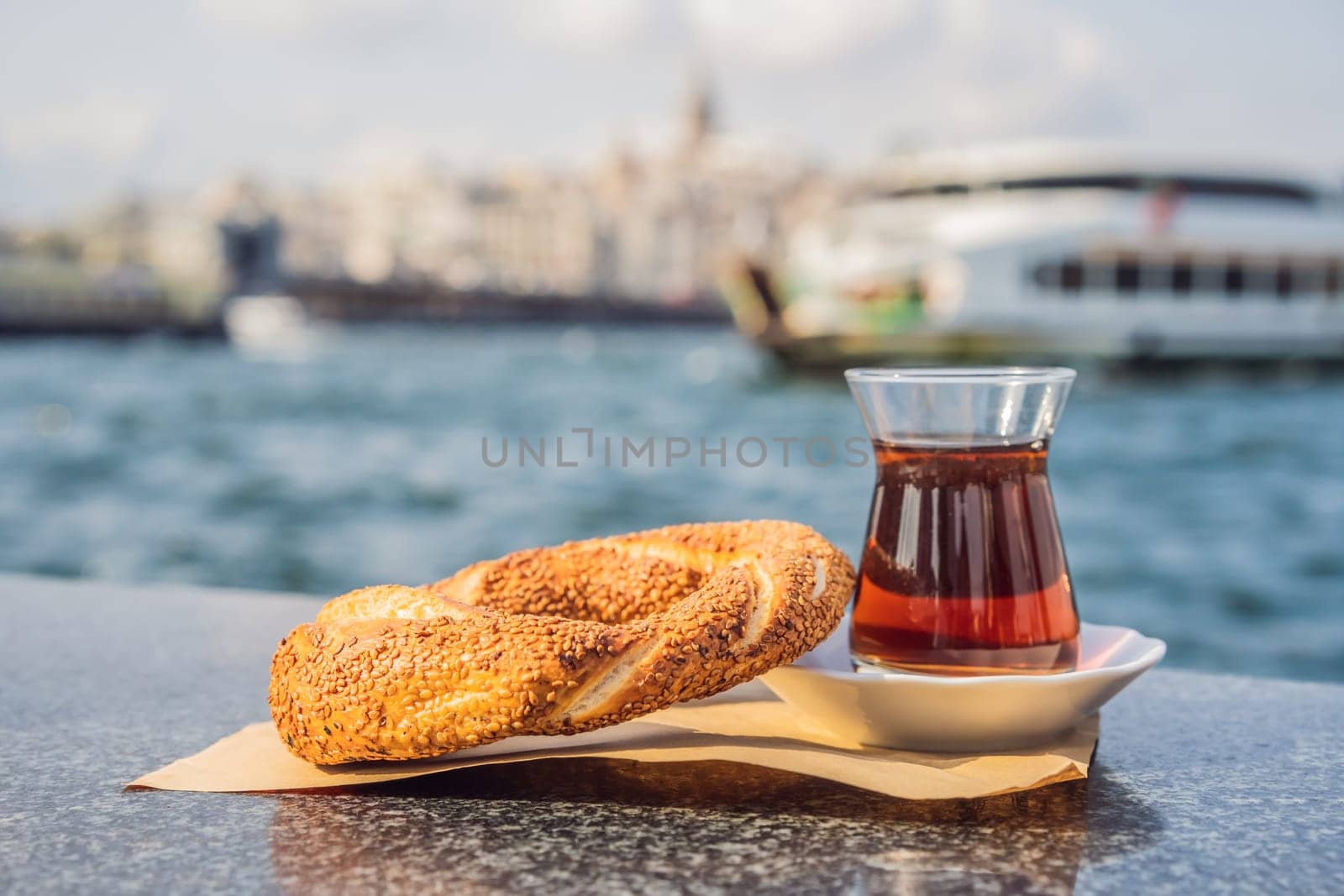 A glass of Turkish tea and bagel Simit against golden horn bay in Istanbul, Turkey. Turkiye by galitskaya