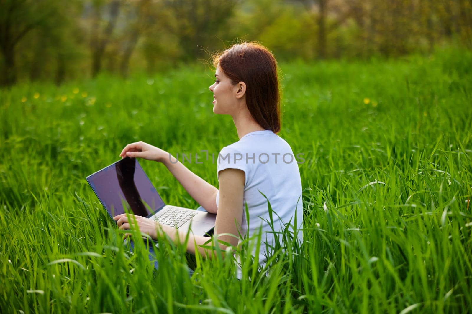 Business woman relaxing in green grass field outdoor under sun. Bright sunny day. High quality photo