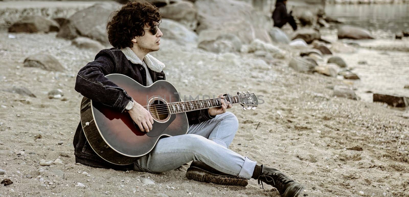 Lone musician playing guitar on the beach by pippocarlot