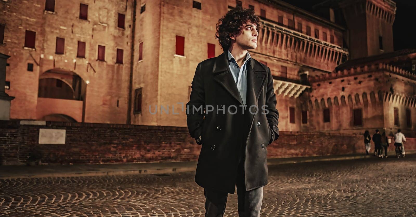 A lone figure in a long coat gazes thoughtfully at the bustling cityscape under the cover of darkness.