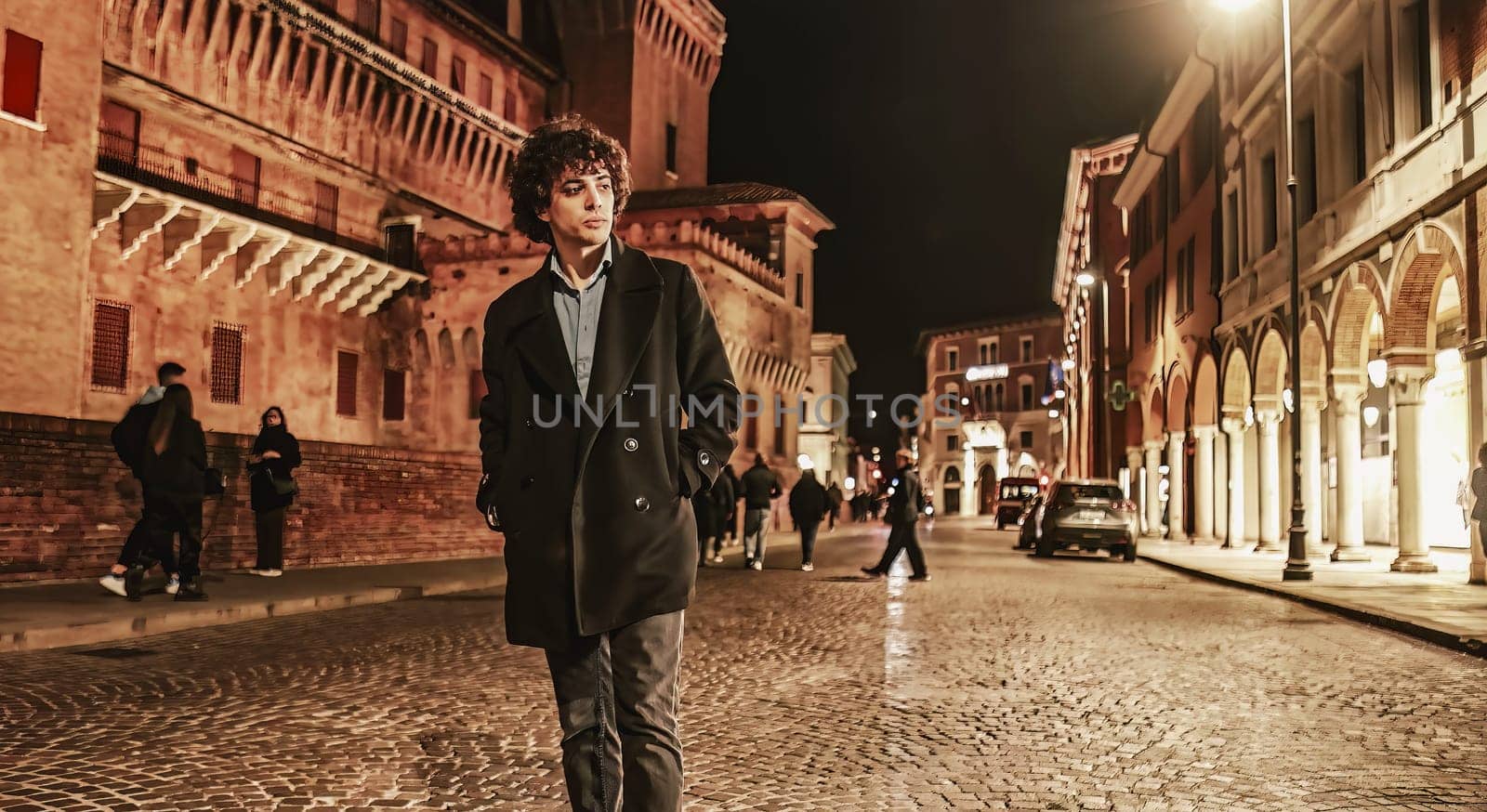 A young man is walking alone in an urban setting at night, with dark shadows and the bright lights of the city creating a dramatic atmosphere.