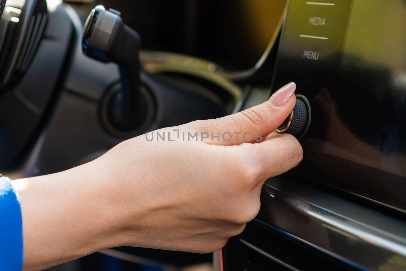 Close up woman in blue blazer change the volume on the infotainment sitting in the car.