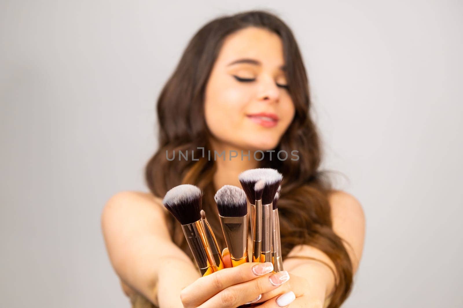 Cosmetic brushes for professional makeup in woman hands on the grey background by vladimka