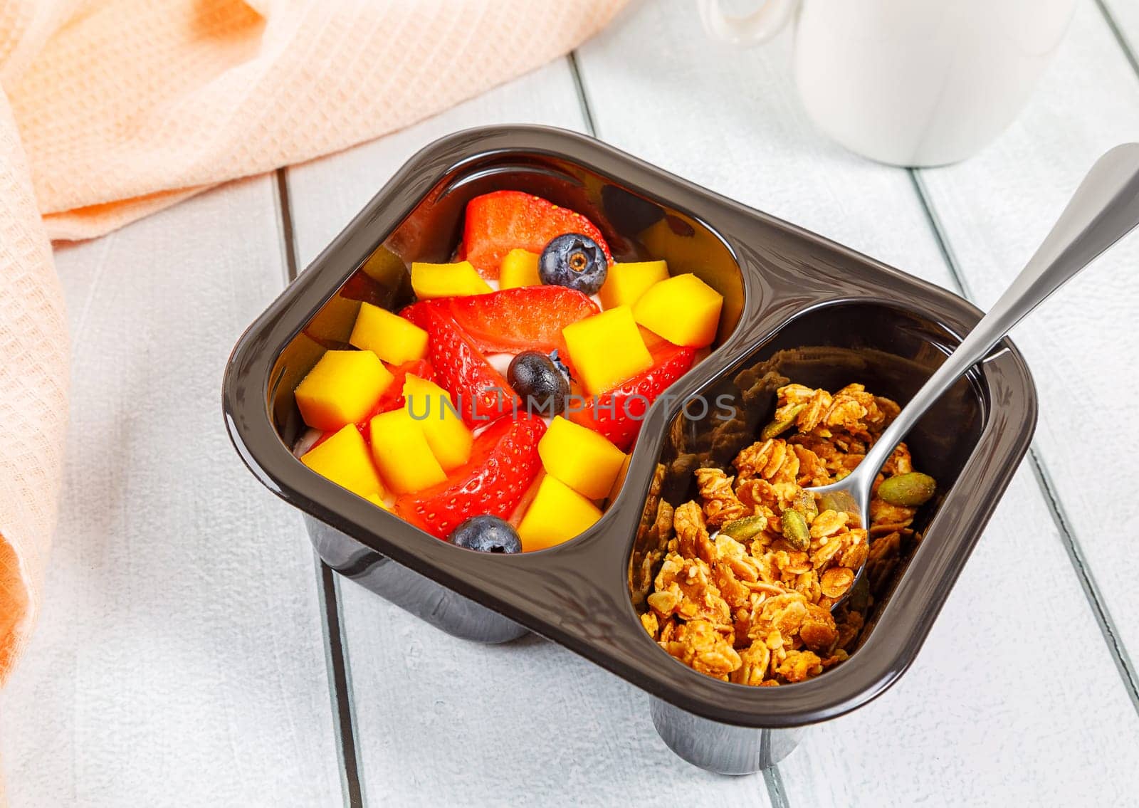 Dessert of cream, mango, strawberries and muesli on a wooden background. High quality photo