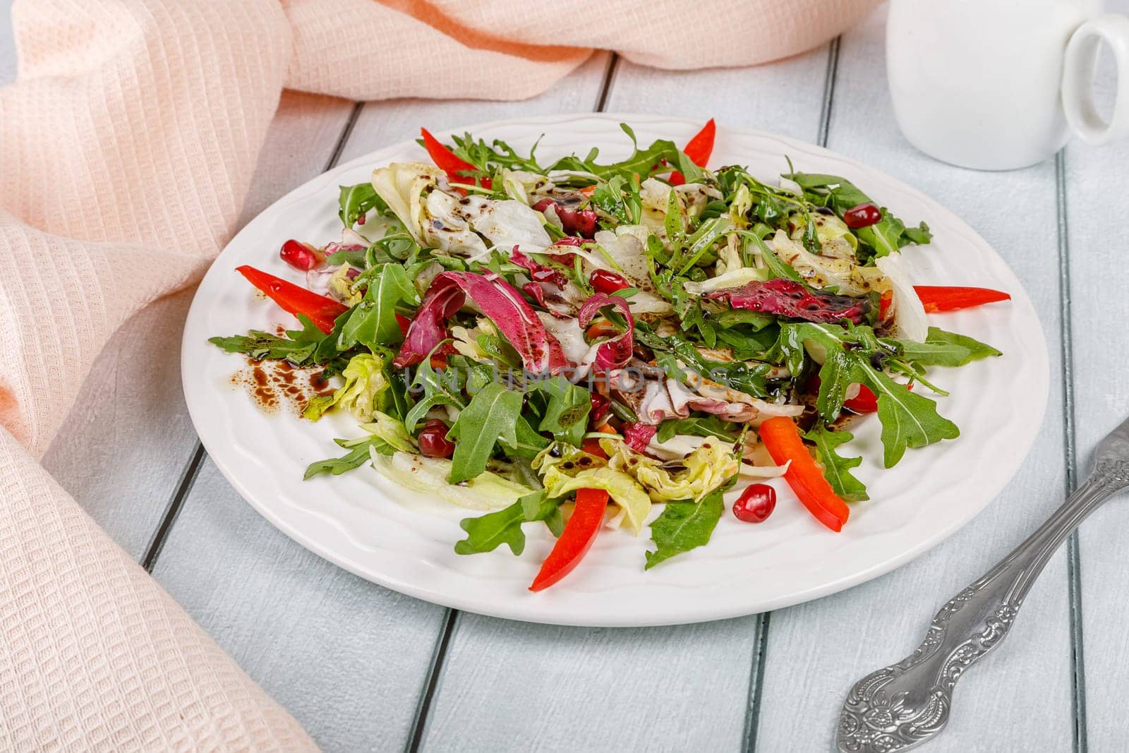 Fresh salad of cabbage, herbs, peppers, carrots and pomegranate seeds in a white plate. High quality photo