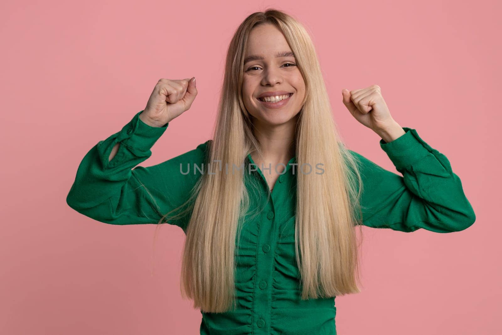 Happy joyful caucasian woman shouting, raising fists in gesture I did it, celebrating success, winning, birthday, lottery jackpot goal achievemen, good news. Young adult girl on pink studio background