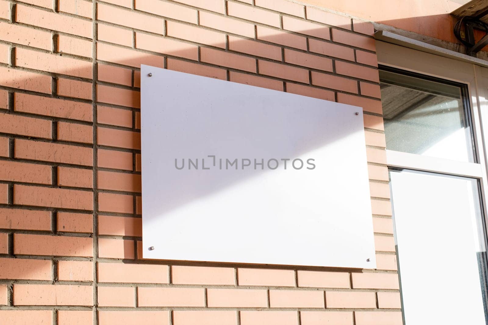 white rectangle logo on brick wall building exterior for mockup design by Desperada