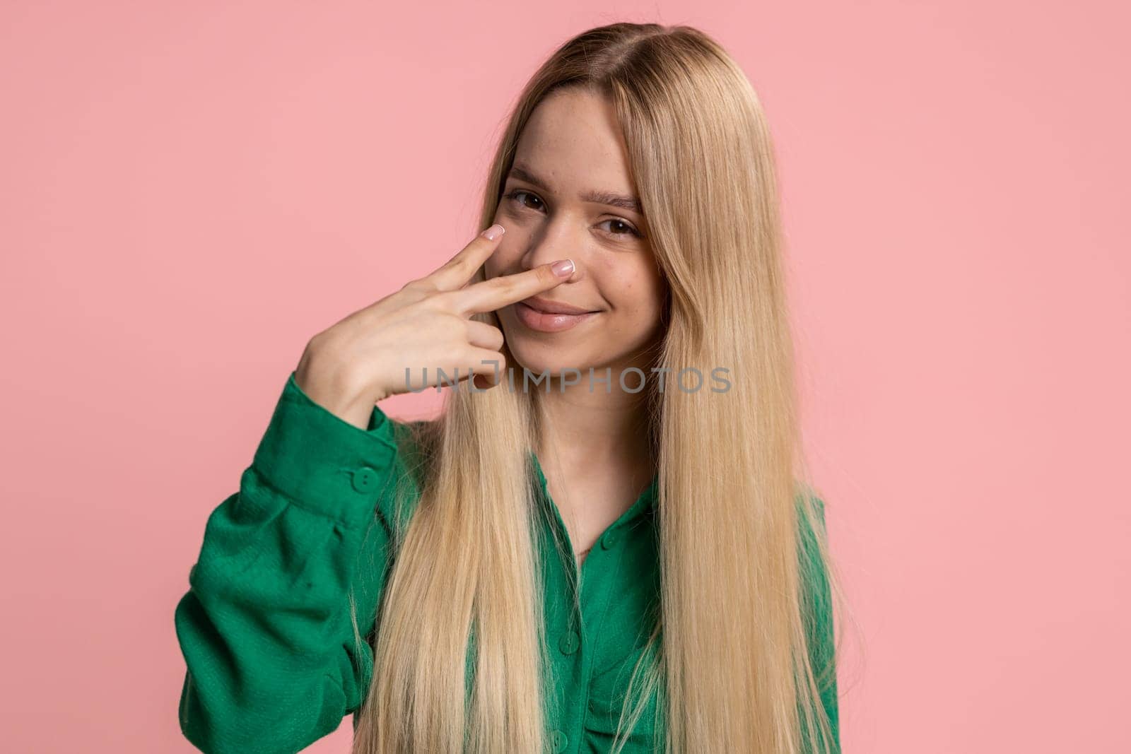 I am watching you. Young confident caucasian woman pointing at her eyes and camera, show I am watching you gesture, spying on someone. Pretty teenager girl isolated alone on pink studio background