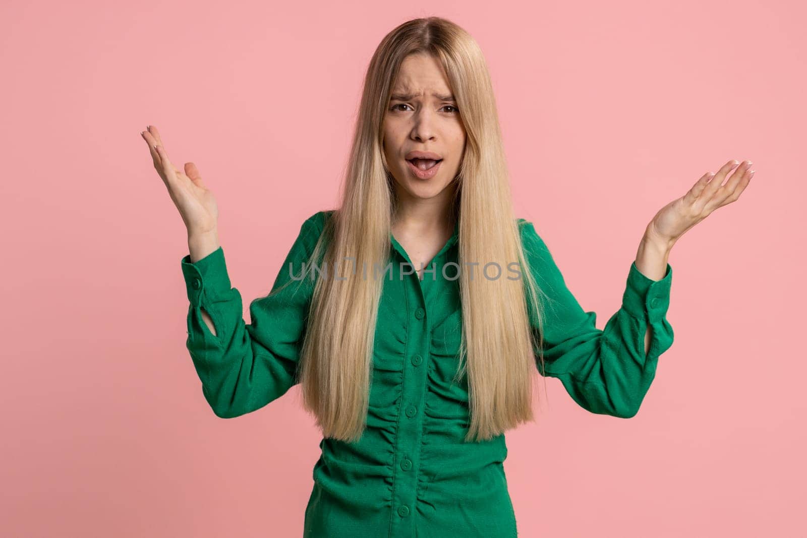 What. Why. Sincere irritated caucasian woman raising hands in indignant expression asking reason of failure demonstrating disbelief irritation by trouble. Pretty confused girl on pink wall background