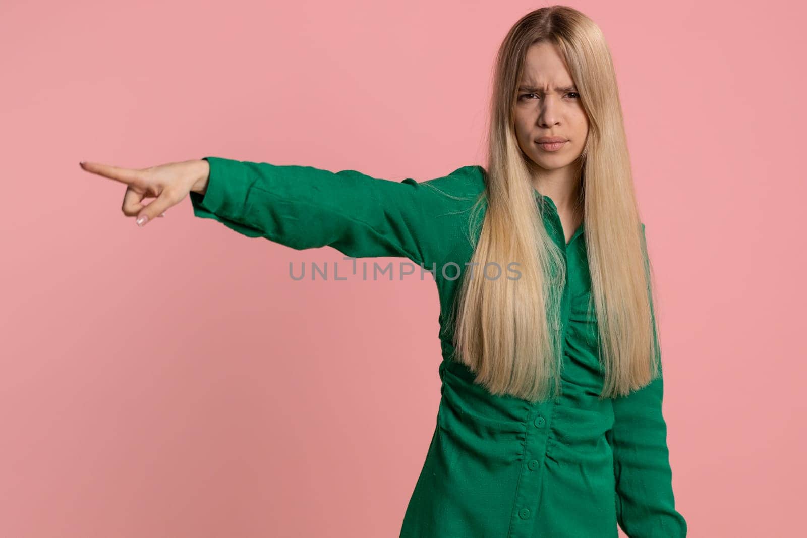 Get out of here. You are fired. Young irritated caucasian woman pointing finger away asking to leave him alone, strict boss firing, conflict. Pretty girl isolated on studio pink background indoors