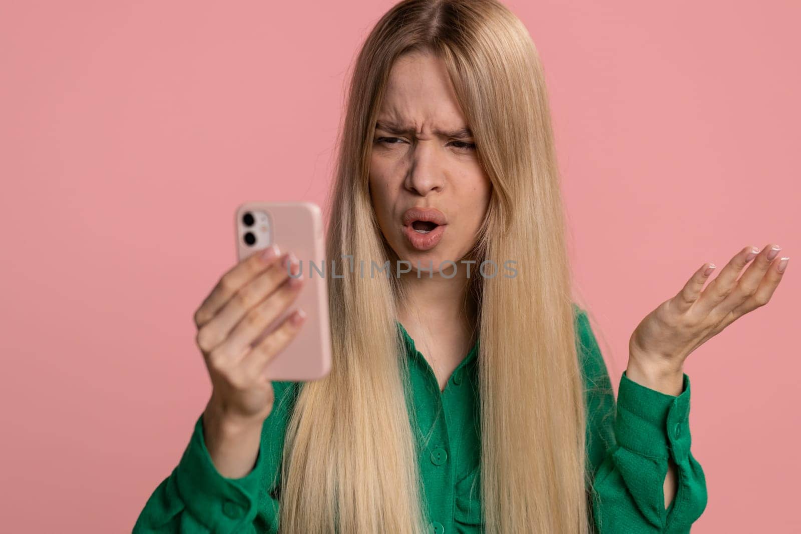 Caucasian woman use mobile cell phone typing browsing, loses becoming surprised sudden lottery results, bad fortune, loss, fail. Pretty one girl isolated alone on pink studio wall background, indoors